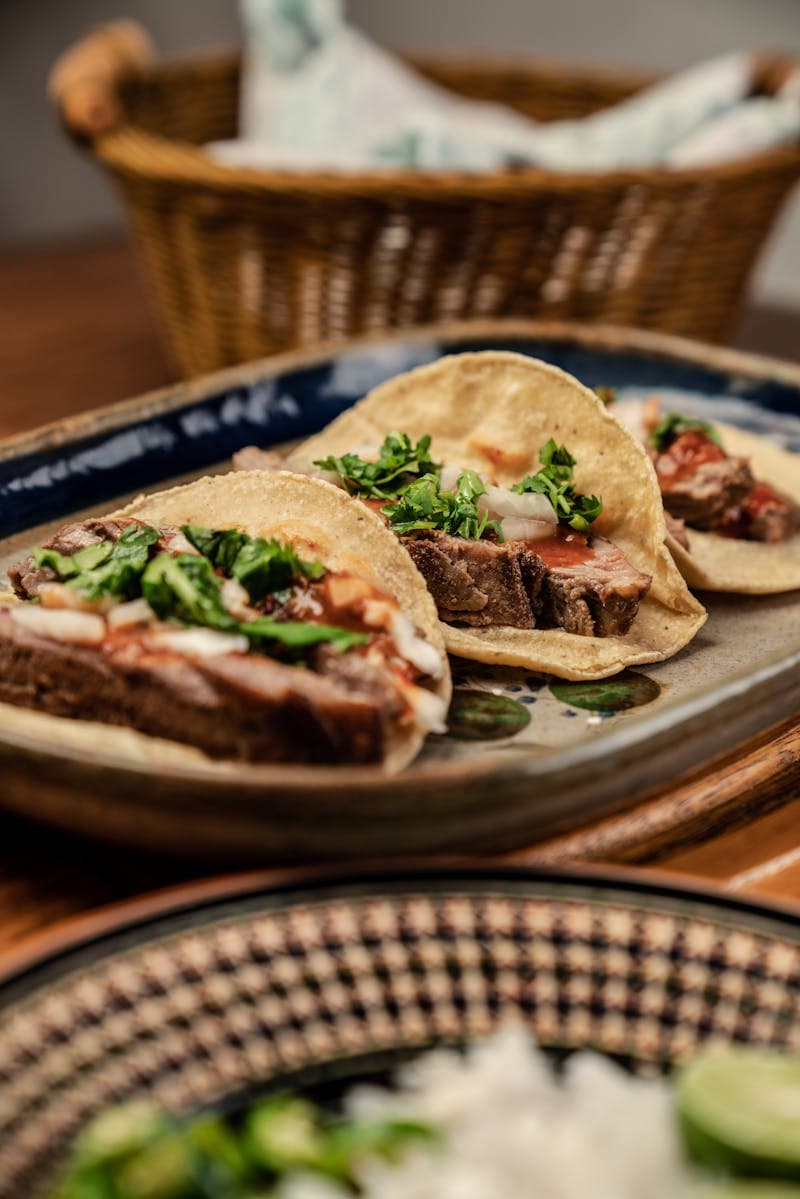 Tacos laid out on a board with lime, coriander and salsa